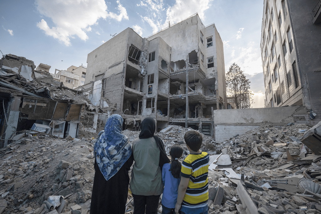 An Iranian family visits a destroyed residential building targeted amid the Iran-Israel war. AFP